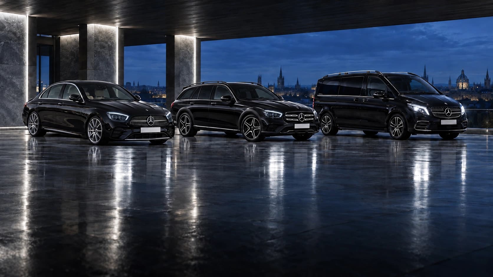 The black Mercedes E-Class Saloon, E-Class Estate and Vito parked side by side under a stone pavilion at dusk, Oxford's spires beyond