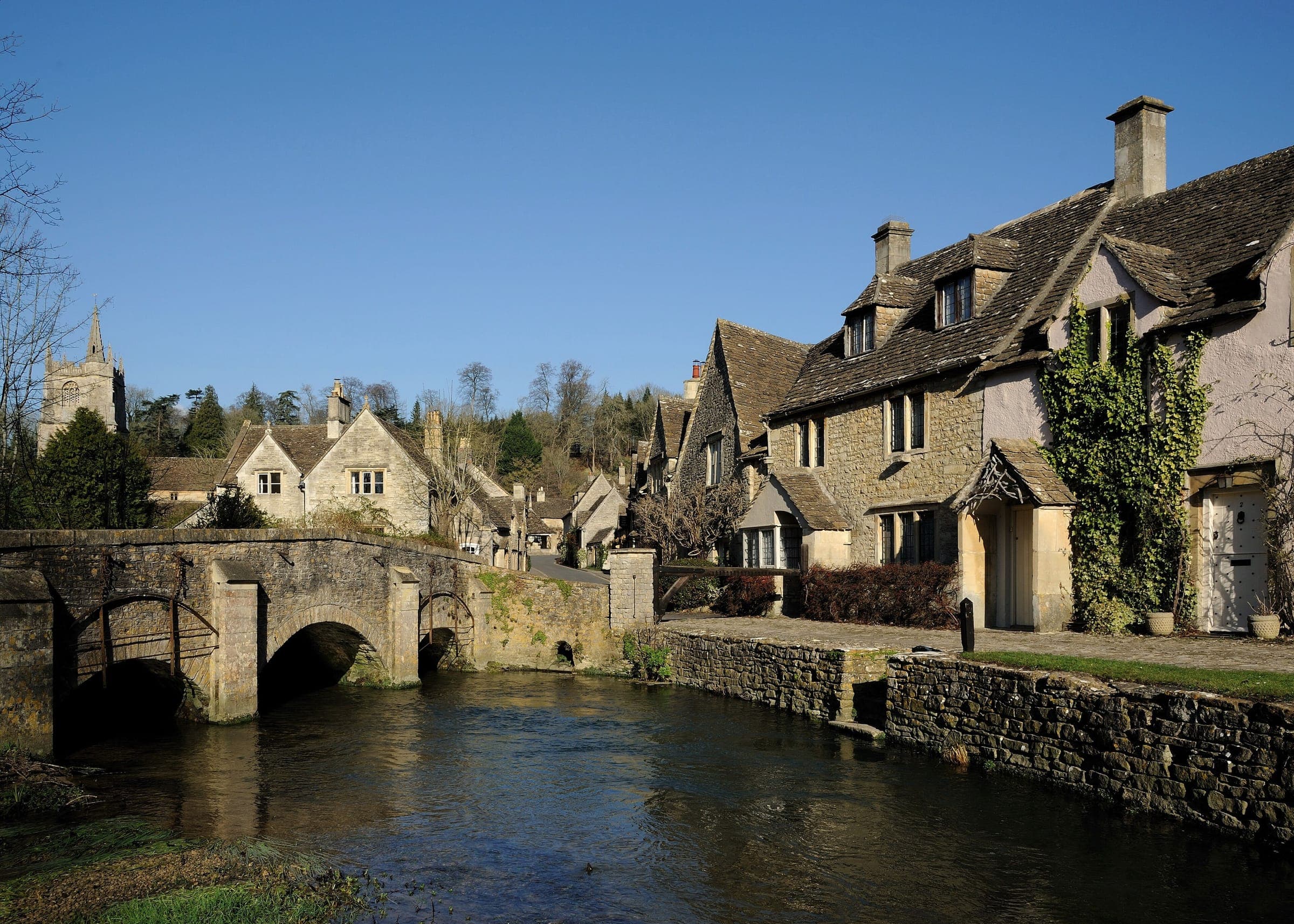 The old stone bridge over the By Brook at Castle Combe, with honey-coloured cottages beyond